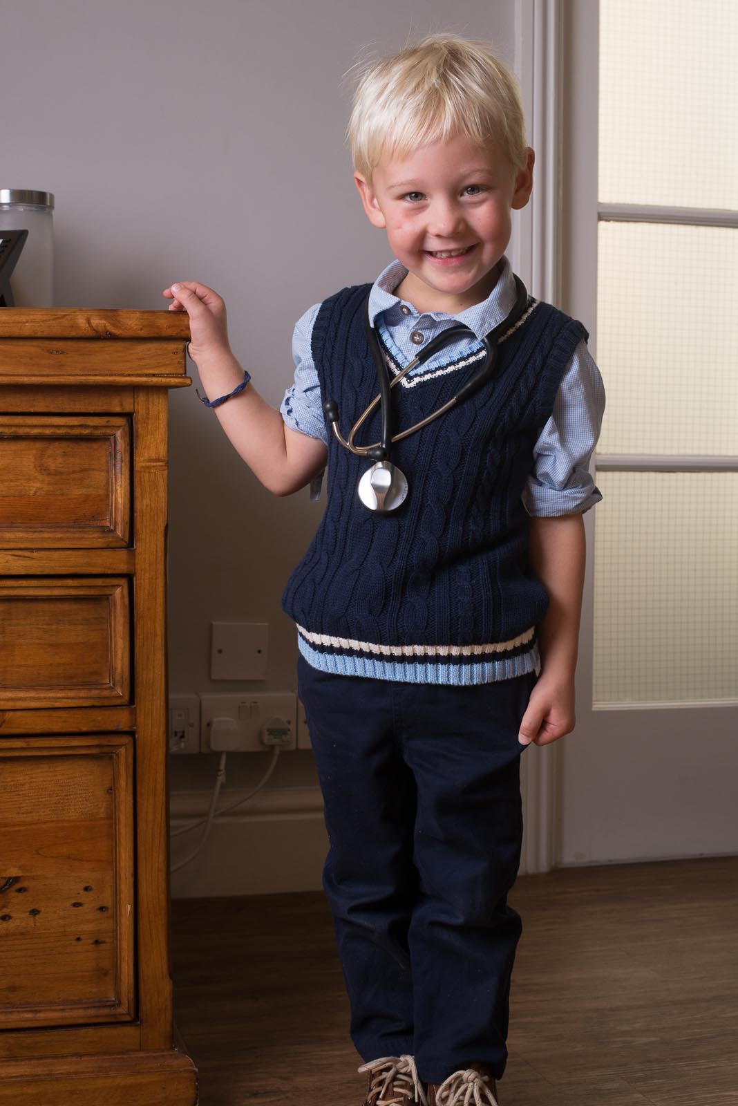 Young boy playing doctor and grinning with a stethoscope around his neck