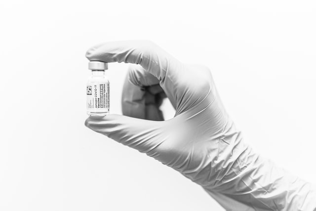 Vaccination bottle held by a doctor wearing surgical gloves