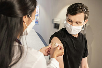 A Health Care Provider placing a dressing on the injection site of a patient